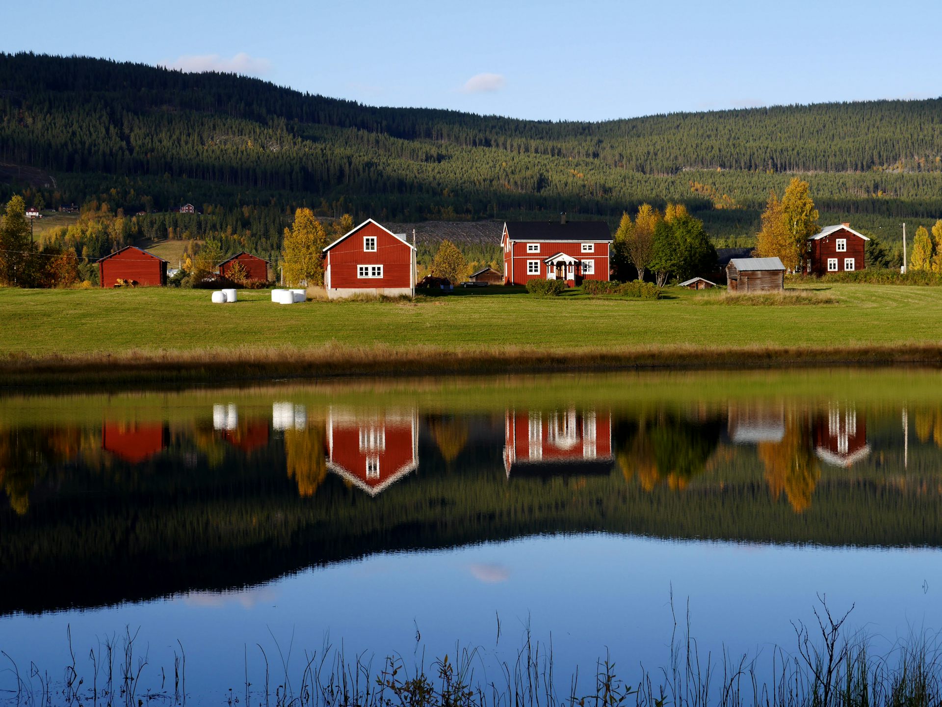 Traditional wooden houses in Sweden mirroring in a fresh water lake in the afternoon sun
