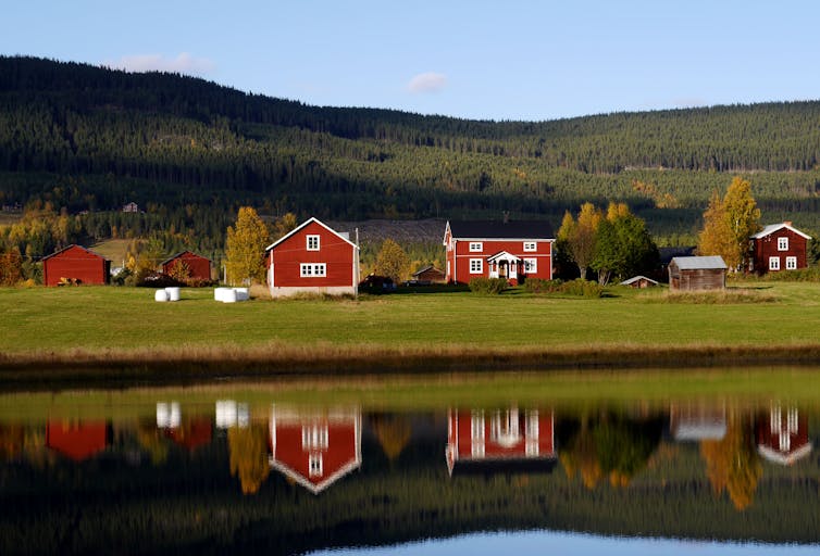 Traditional wooden houses in Sweden mirroring in a fresh water lake in the afternoon sun
