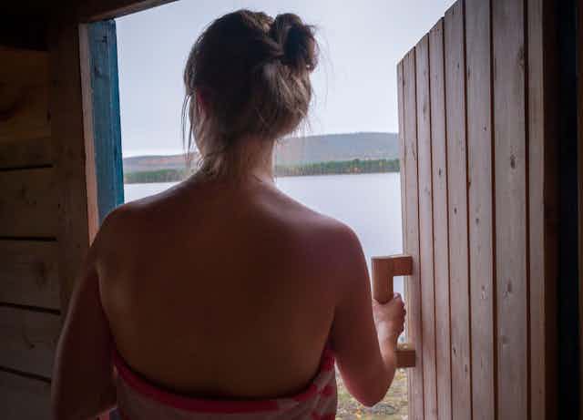 Woman leaves sauna by a lake.