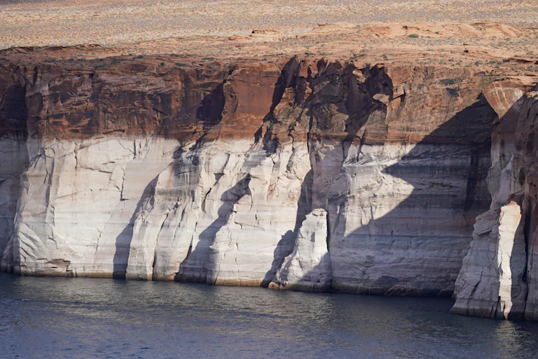 A rock cliff wall, the lower two-thirds white and the upper third red.