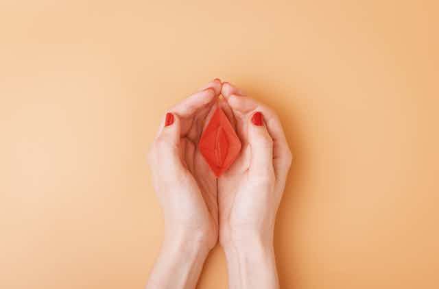 small red paper boat in female palms