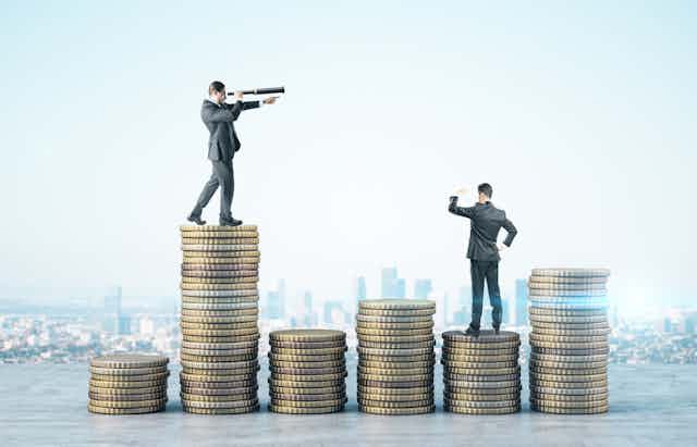  Business people, suits, with telescope standing on golden coins on city background.