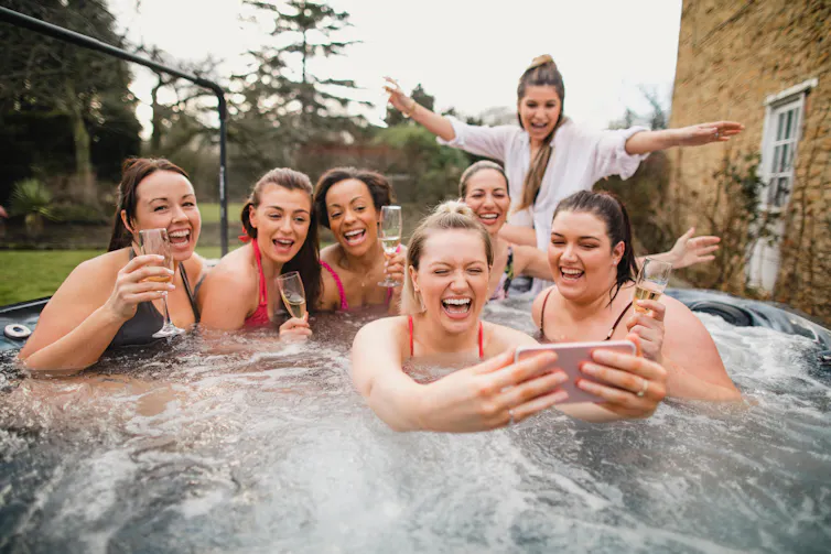 Women in hot tub taking a photo.