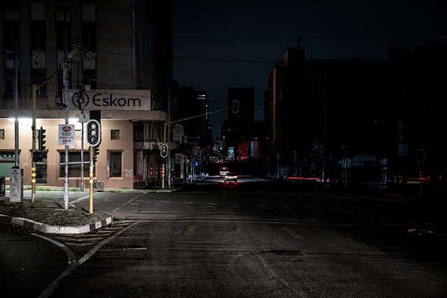 An illuminated signboard shows the name 'Eskom' on a street without lights.