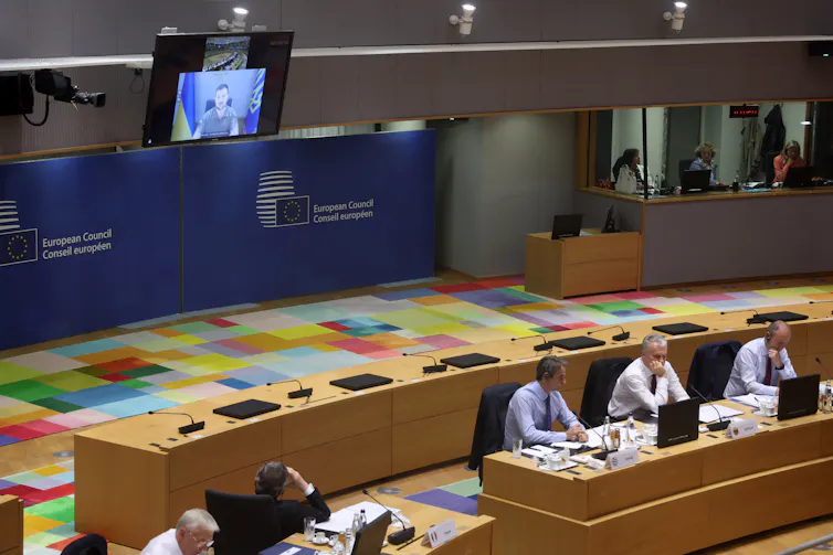 Members of the EU Council sit in session listening to the Ukrainian president Volodymyr Zelensky deliver an address via video link.
