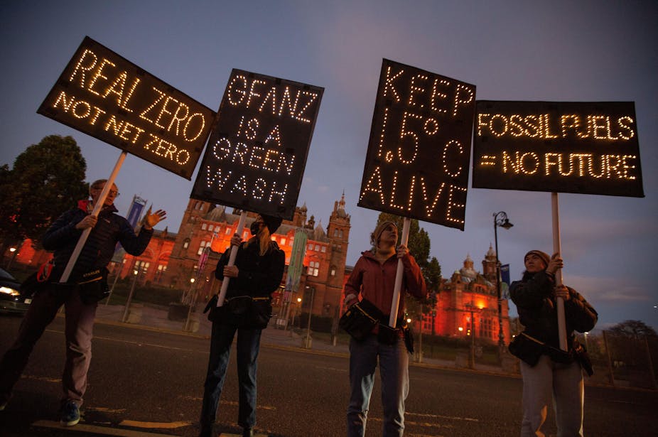 Four climate action protestors each holding a sign aloft. 