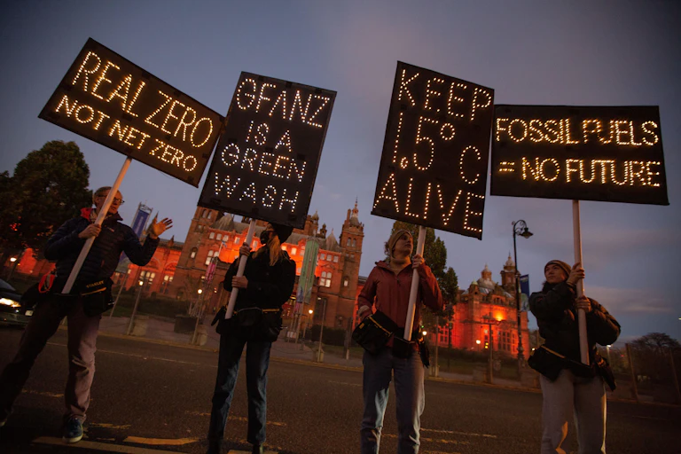 Four climate action protestors each holding a sign aloft.