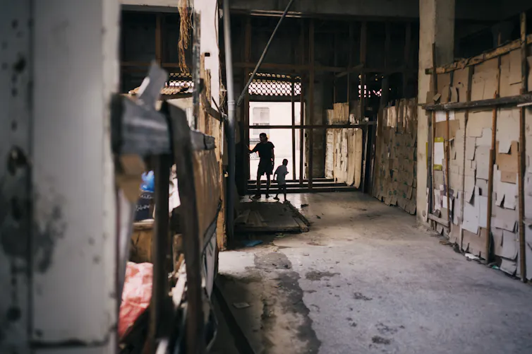 Un joven cubano y un niño juegan en el pasillo de un edificio abandonado - La Habana, Cuba, diciembre de 2022.