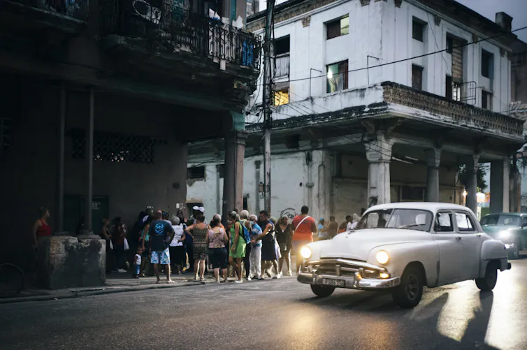 multitud hace cola para comprar comida al atardecer en La Habana, Cuba, diciembre de 2022