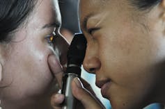 a doctor looks into a patient's eye with an instrument