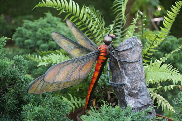 sculpture de libellule génate noire et orange. Échapper aux prédateurs.