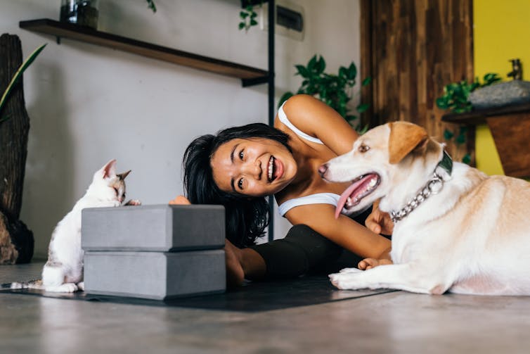 Woman doing yoga with dog and cat.