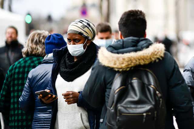 Photo de gens portant des masques dans la rue.