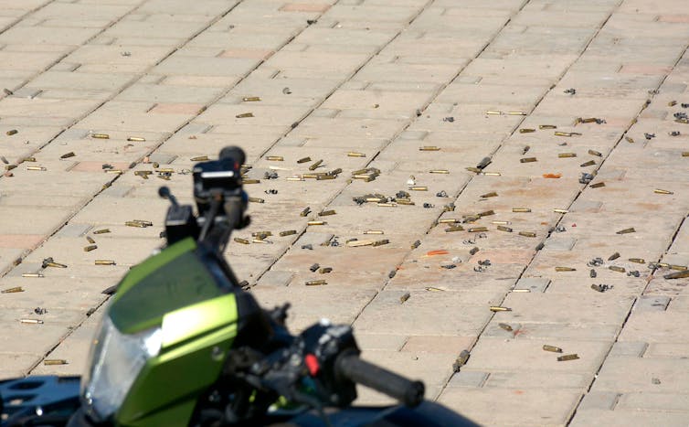 Many small metal bullet casings are seen scattered on a beige ceramic tile floor outside.