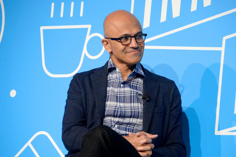 Bald man wearing glasses smiles while looking to the side.