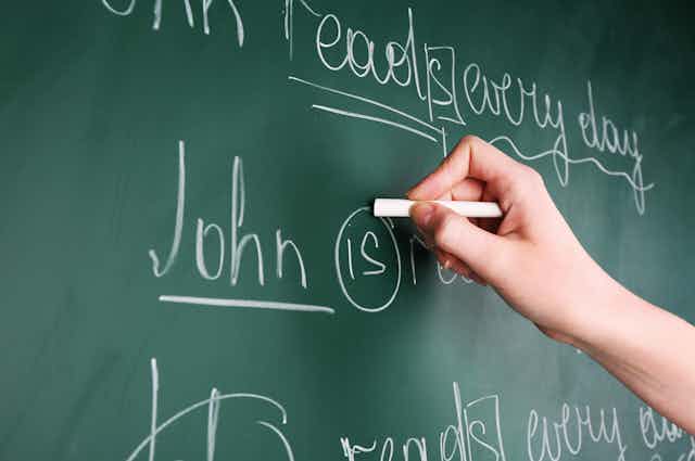 Writing on a chalkboard, 'John is ...'