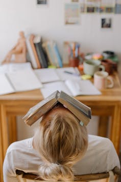 يتعلم الطالب من المكتب مع كتاب على وجهه.
