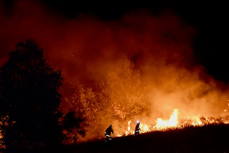 firefighters silhouetted against flames