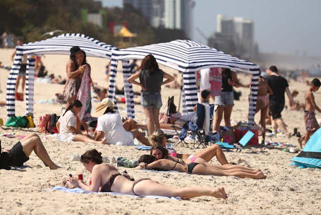 Beach cabanas at Australian beach, sun bakers lying on sand