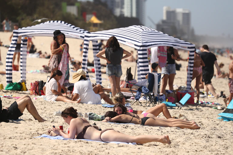 Beach cabanas at Australian beach, sun bakers lying on sand
