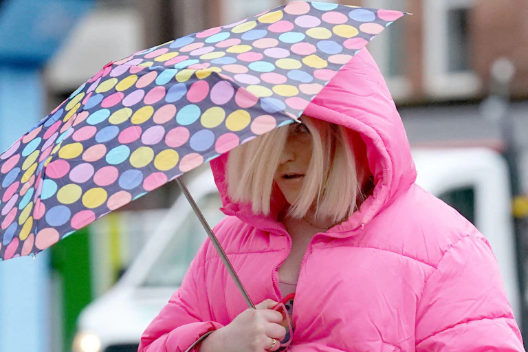 Isla Bryson wearing a pink coat and holding an umbrella.