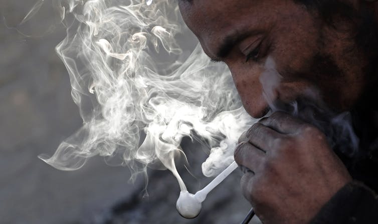 An Afghan man smoking an opium pipe.