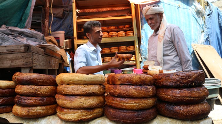 Dois homens atrás de grandes queijos