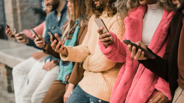 People on a bench using smartphones.
