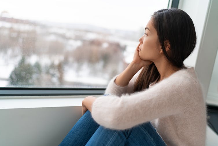 Asian woman looks out a window.