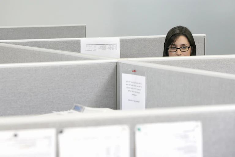 woman peeks out over cubicles