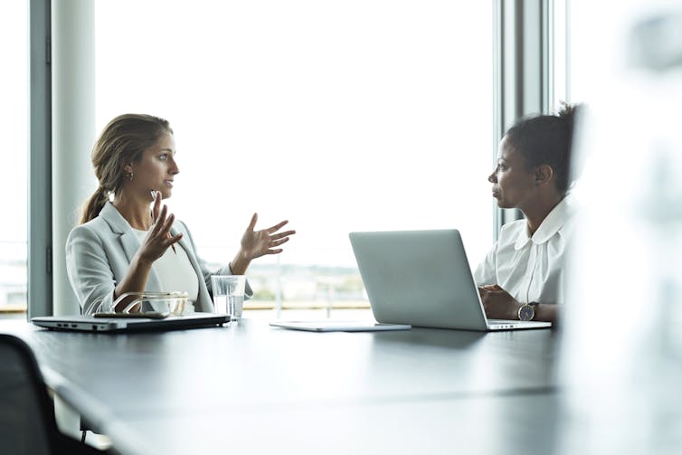 two women talk at a conference table