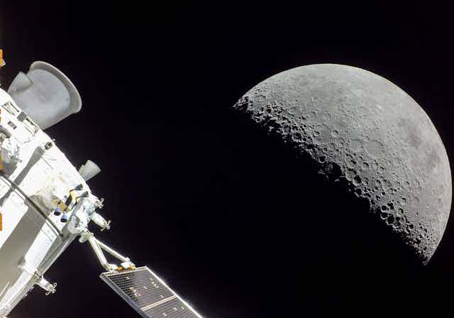 A space craft with the Moon in the background.
