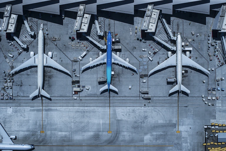 Three airplanes in a row at gates with lots of attendant vehicles preparing them for the next flight.