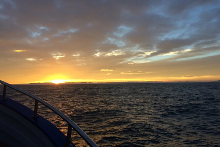 The sun sets over the ocean, viewed from a boat at sea
