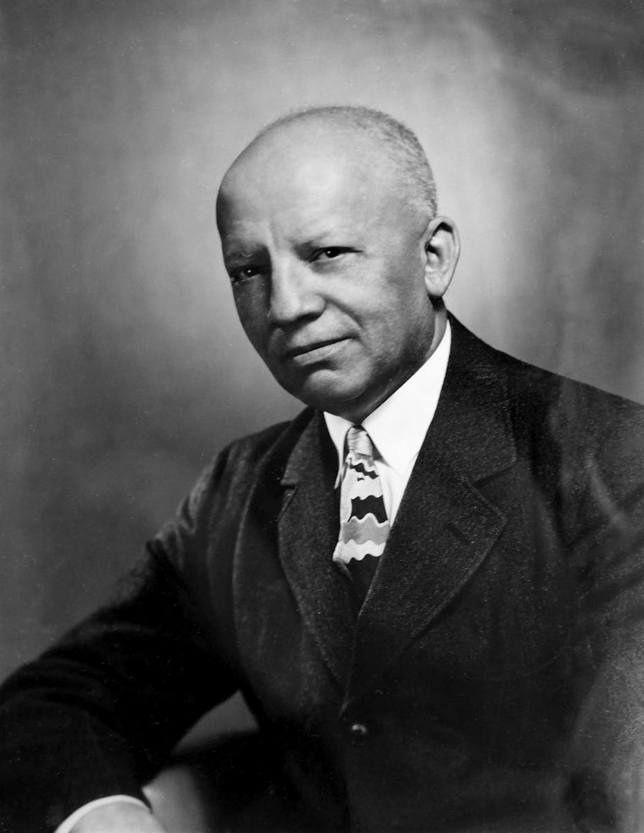 An elderly black man dressed in a dark business suit poses for a portrait.