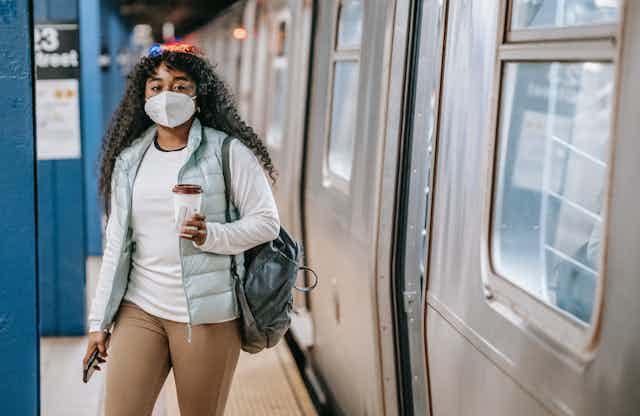 Woman steps out of a train wearing a mask