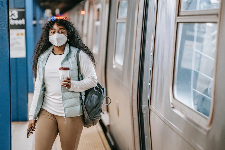 Woman steps out of a train wearing a mask