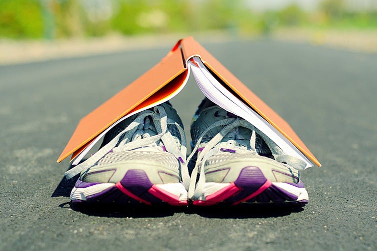 Zapatillas de deporte tapadas con libro abierto color naranja.