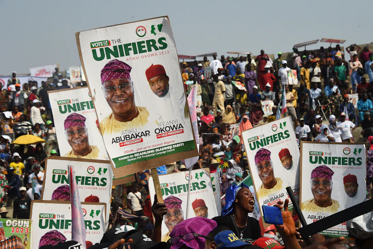 A crowd of part supporters carrying placards at a political rally.
