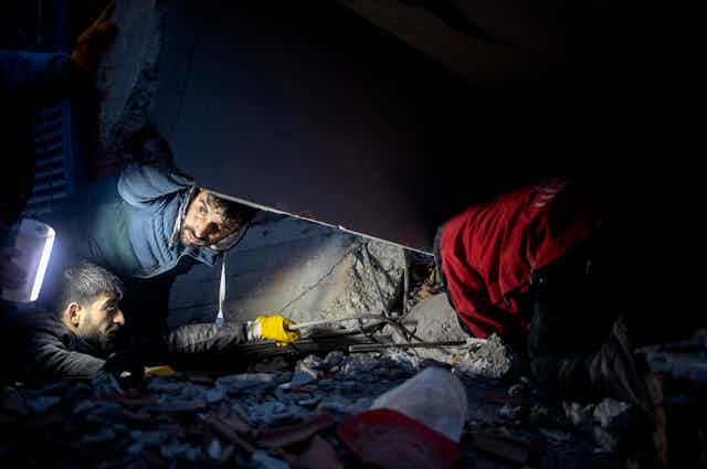 People search through rubble by torchlight.