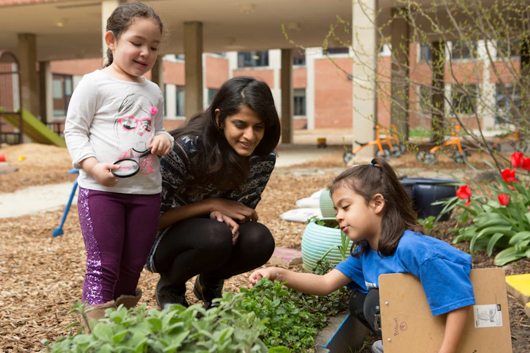 An educator seen in garden with children.