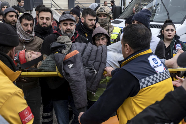 An injured survivor of the earthquake being carried on a stretcher by emergency personnelrn Turkey.