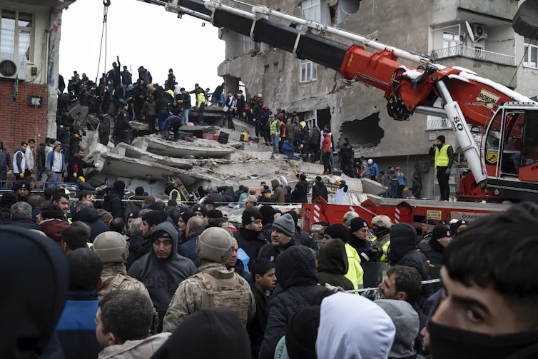 Emergency workers and a crane at the site of a collapsed building after an earthquake in southern Turkey, February 6 2022