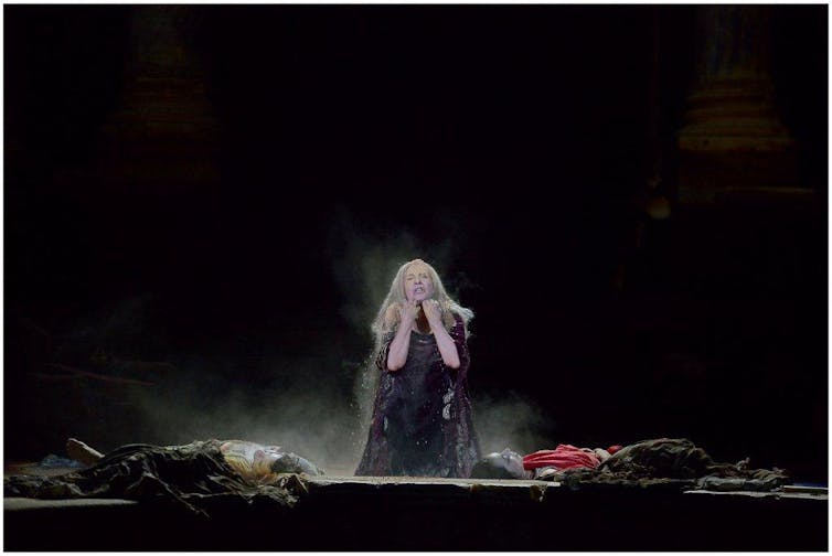 Una mujer de rodillas en un escenario se lamenta.