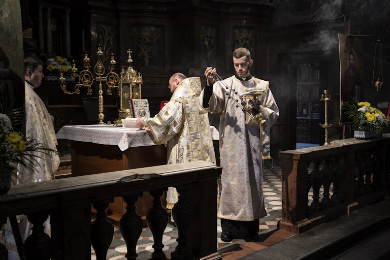 Three priests conducting rituals around an altar.
