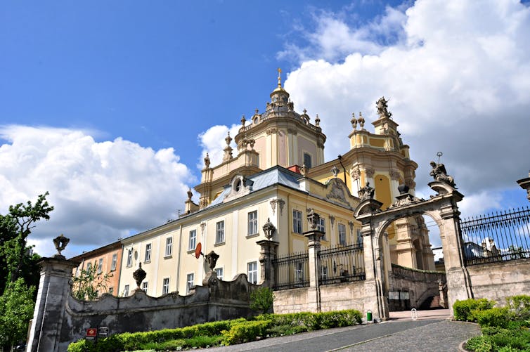 An Orthodox Church building with ornate domes set against a backdrop of blue sky and white clouds.