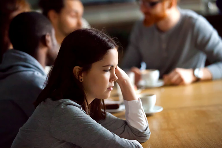 Une jeune femme reste à l'écart, songeuse, de son groupe d'amis