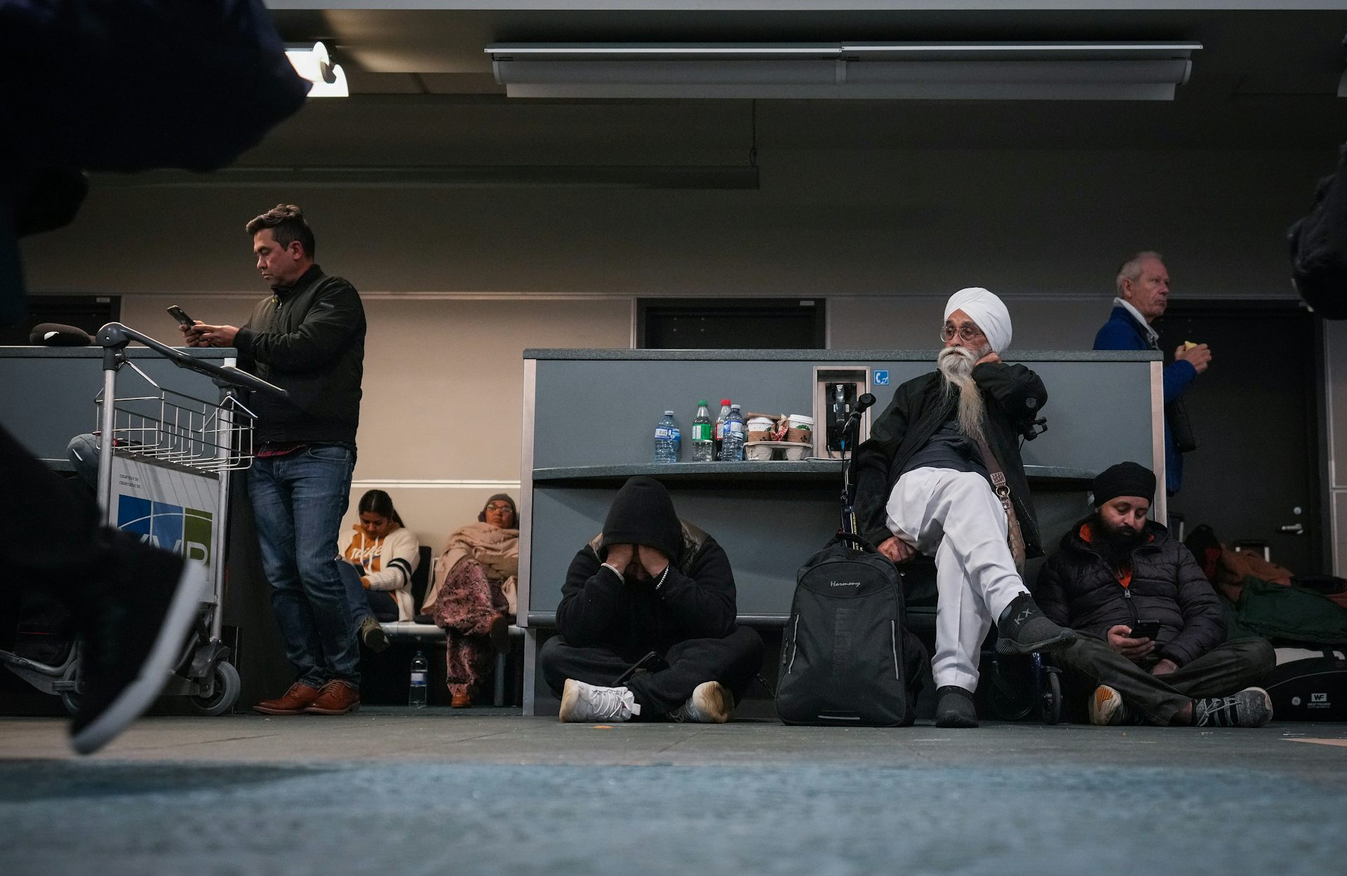 People sit on the floor and on benches in an airport