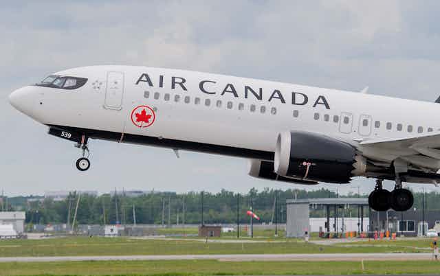 A commercial plane with 'Air Canada' written across the side takes off from the ground