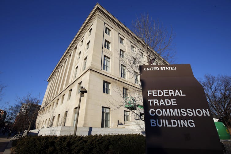A sign that says 'Federal Trade Commission Building' sits in front of a square beige bulidings